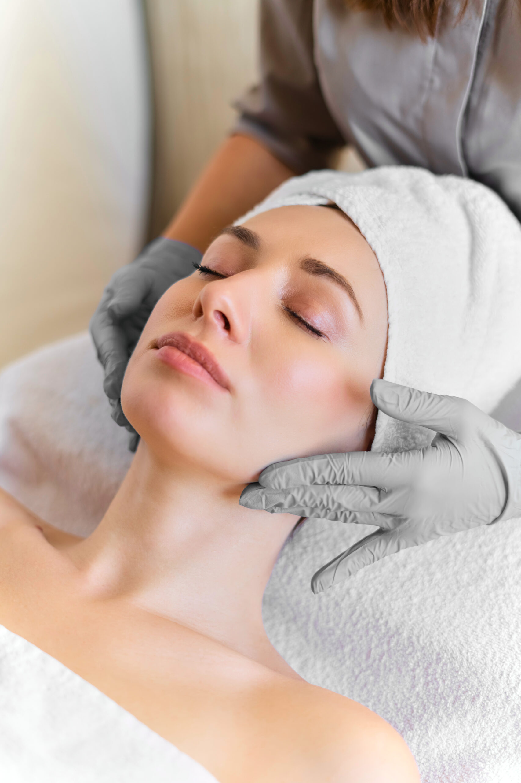 A young beautiful girl lies on the table at the beautician and receives procedures, a light massage, hands in blue gloves, the skin is smooth